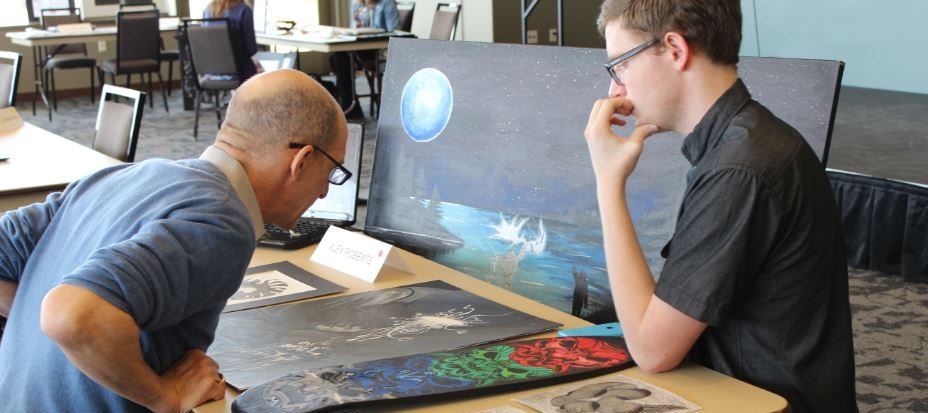 Un estudiante y un artista local discuten su pintura en el Día del Portafolio en Parker Arts.